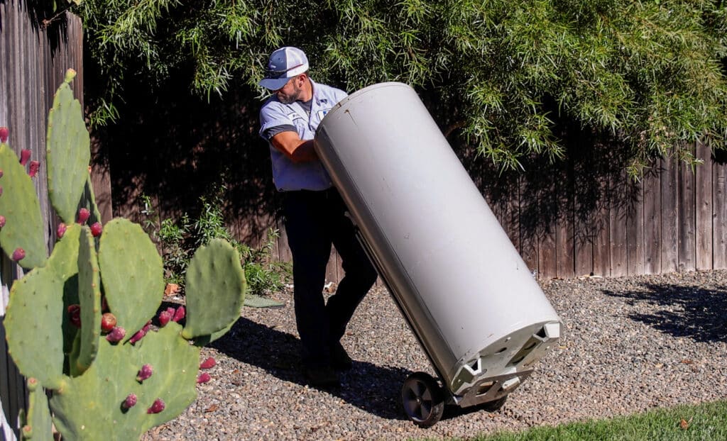 Technician removing an old water heater during a replacement service in Chico CA